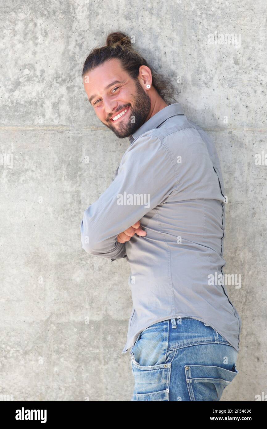 Portrait of smiling man leaning against wall with arms crossed Stock ...