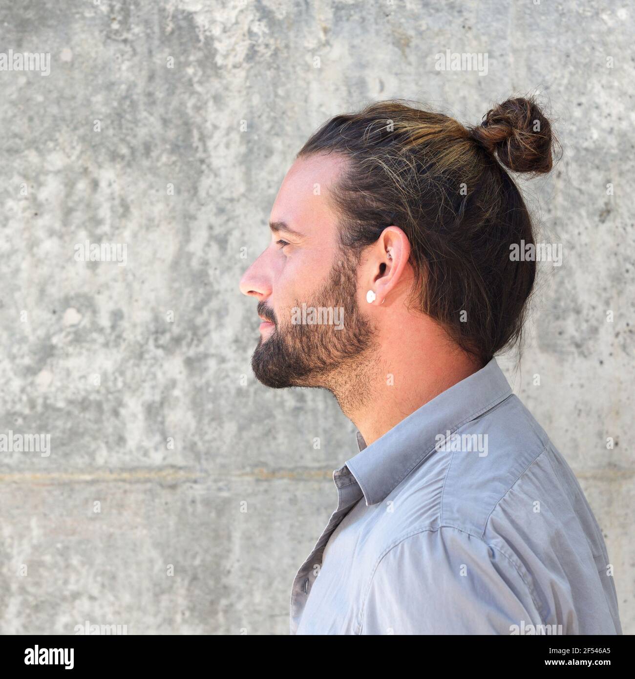 Close up side portrait of serious man with beard and hair bun Stock Photo