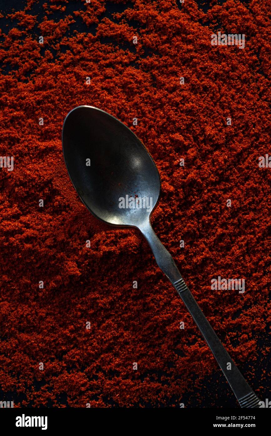 Ground dry red pepper spice, full frame, with old metal teaspoon in the