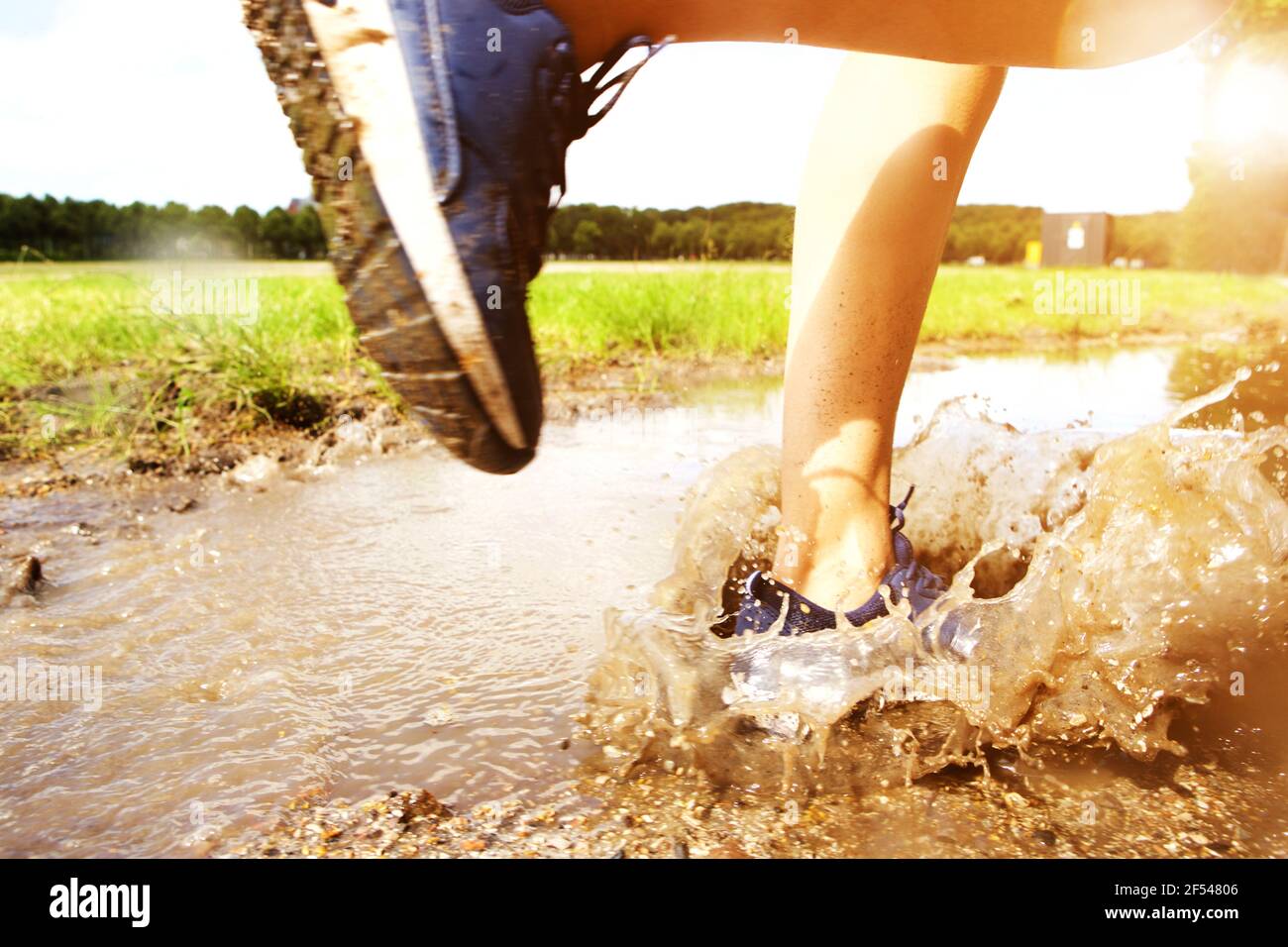 Close up portrait of runner's sneakers splashing in mud puddle Stock Photo