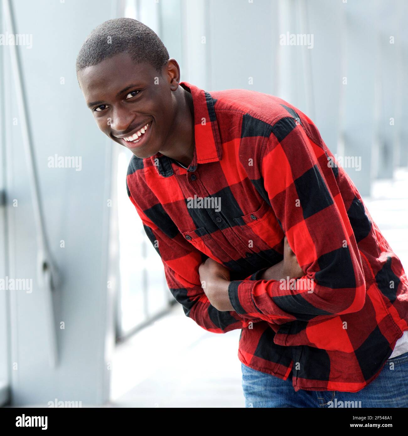 Portrait of happy young african man standing with his arms crossed and ...
