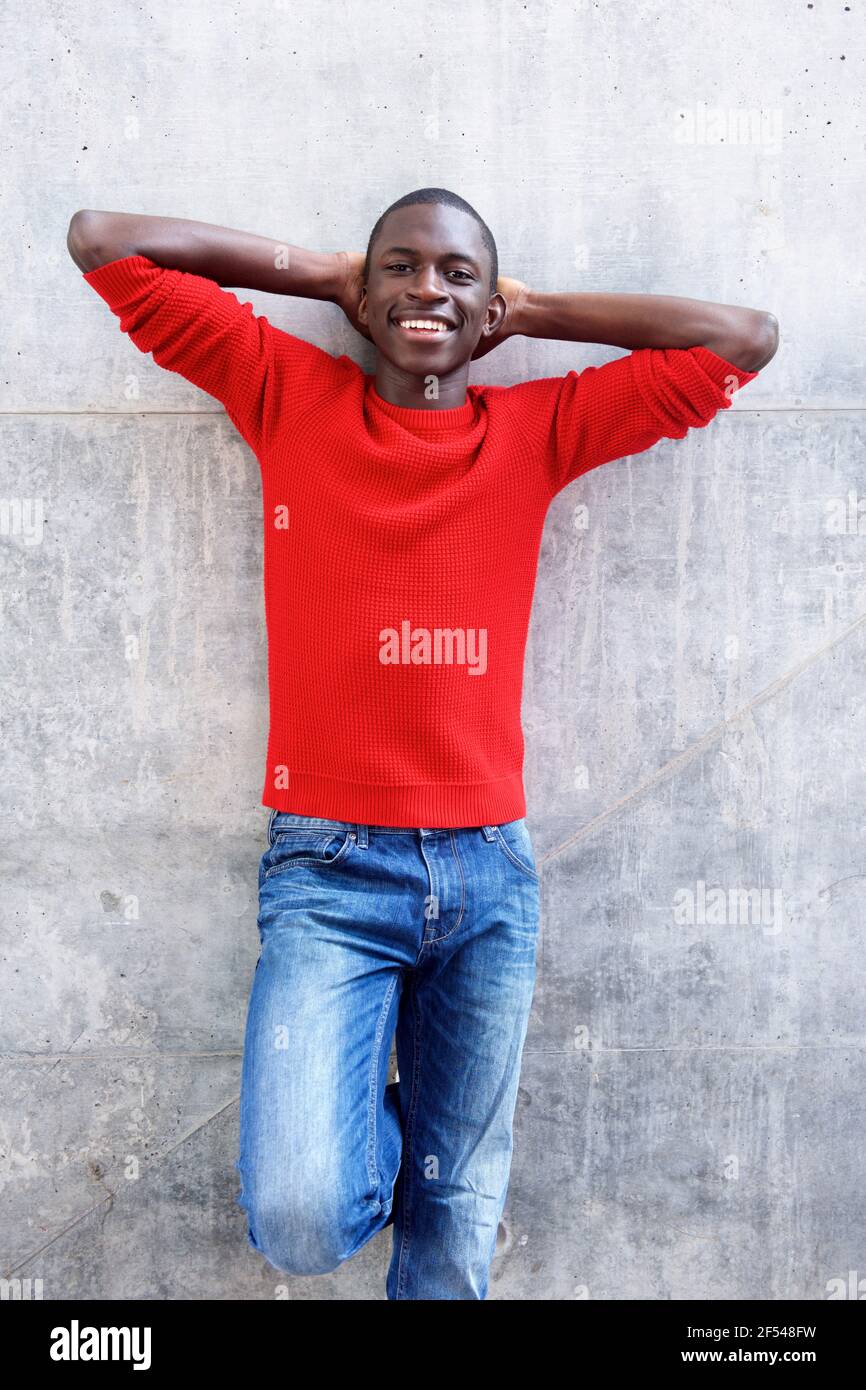 Portrait of handsome young african man standing with hands behind head ...