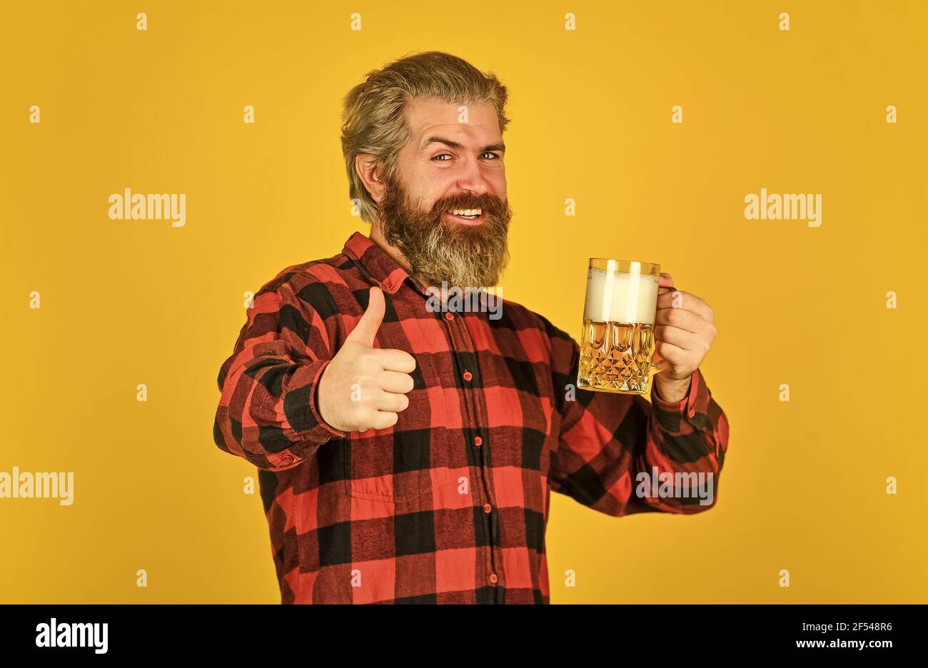 craft beer. Man drinking in pub bar. Beer with foam. brutal hipster drink beer. mature bearded barman hold beer glass. confident bartender raising Stock Photo