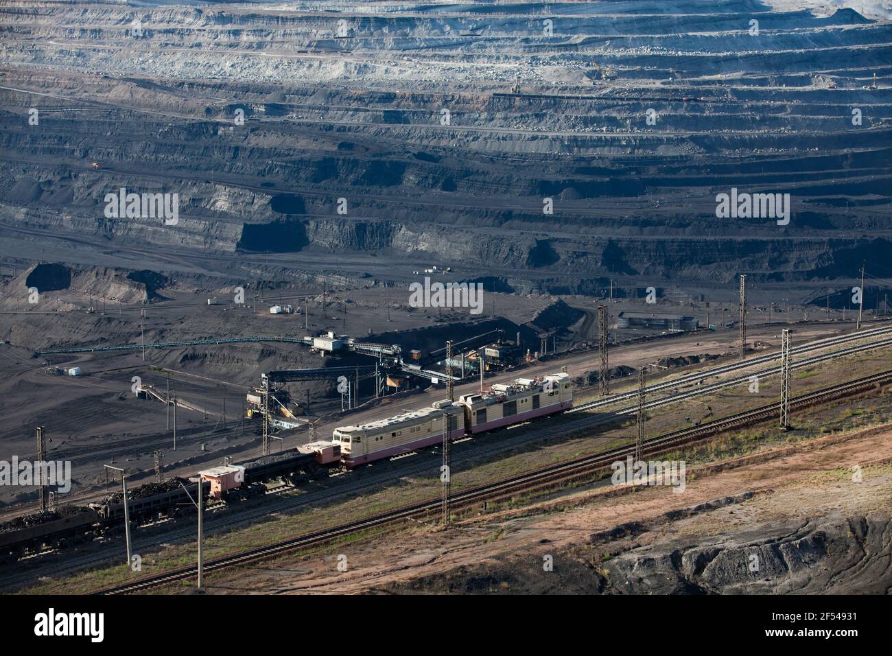 Open pit extraction of coal in quarry 'Bogatyr', Ekibastuz, Kazakhstan. Quarry machine, belt conveyor and loader and train on rails. Stock Photo