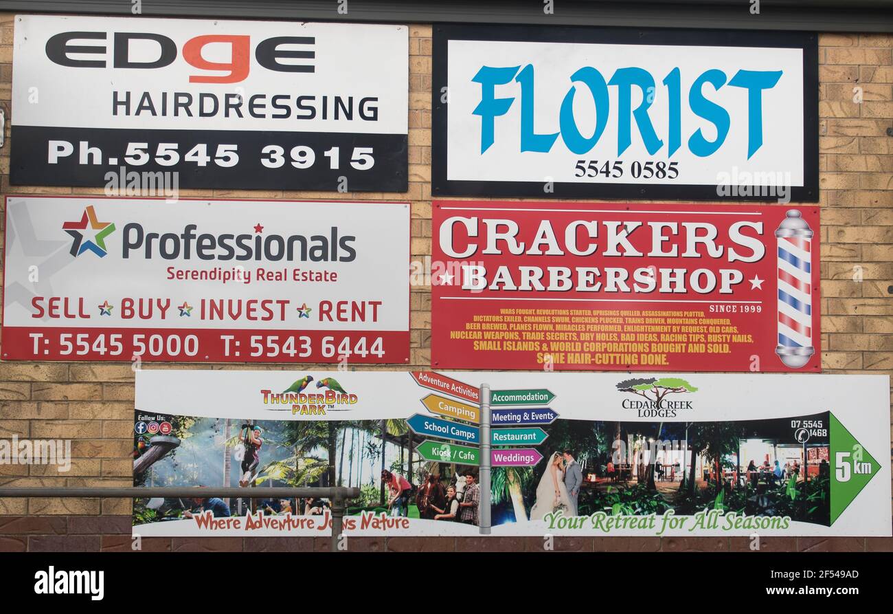 Adverting for local businesses on Tamborine Mountain, Queensland, Australia. Five colourful signs on brick wall for services and shops. Stock Photo