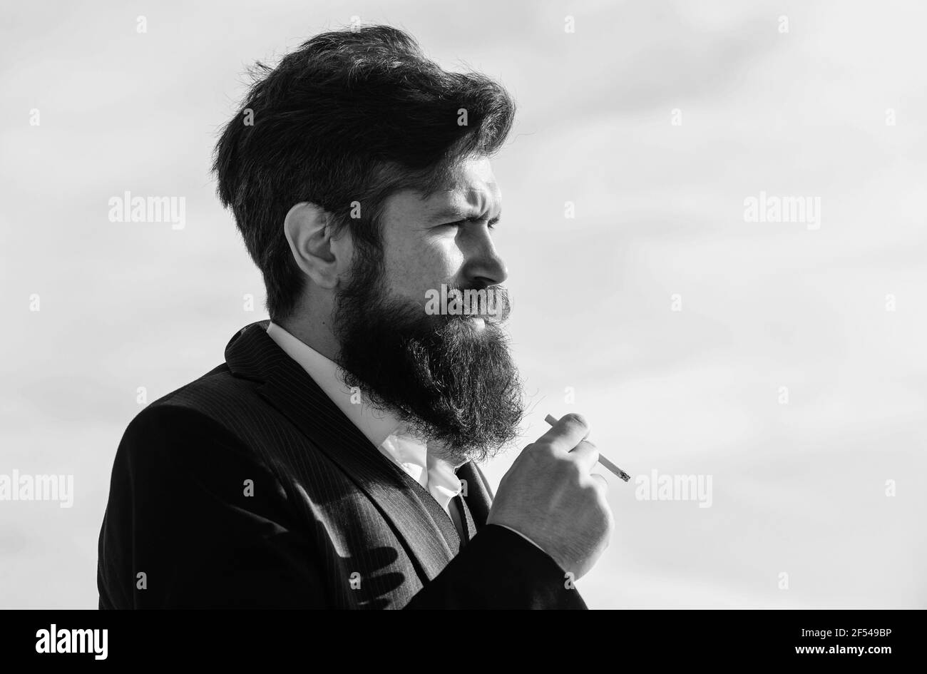 Man with beard and mustache hold cigarette. Bearded hipster smoking