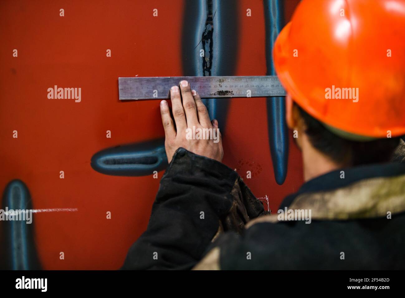 Ekibastuz, Pavlodar region, Kazakhstan May 28 2012: Train car-building plant. Young worker marking car with steel ruler and chalk. no face, hand only. Stock Photo