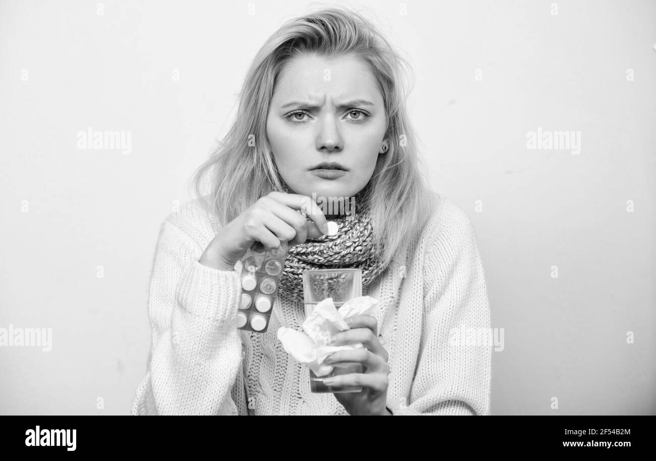 Need another antibiotic. Cute sick girl taking anti cold pills. Unhealthy woman holding pills and water glass. Ill woman treating symptoms caused by Stock Photo