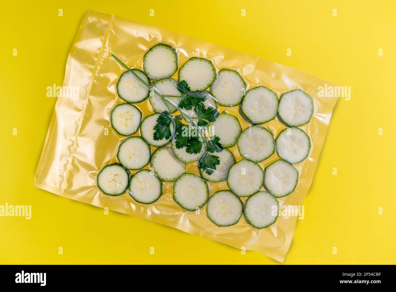 zucchini slice in vacuum packed sealed for sous vide cooking, isolated on yellow background Stock Photo