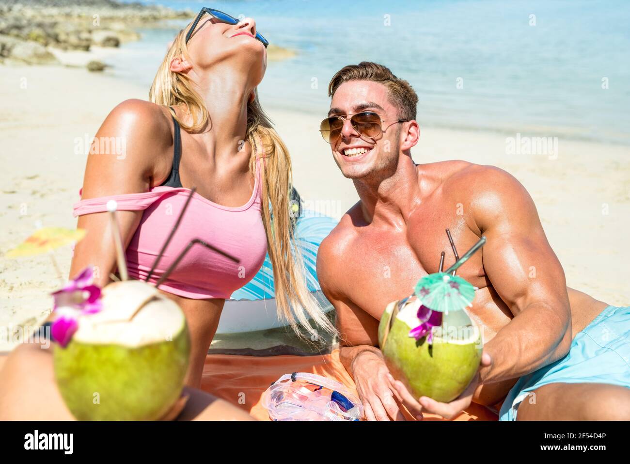 Young couple vacationers drinking cocunut cocktail and having fun on tropical beach in Phuket Thailand - Luxury travel concept Stock Photo