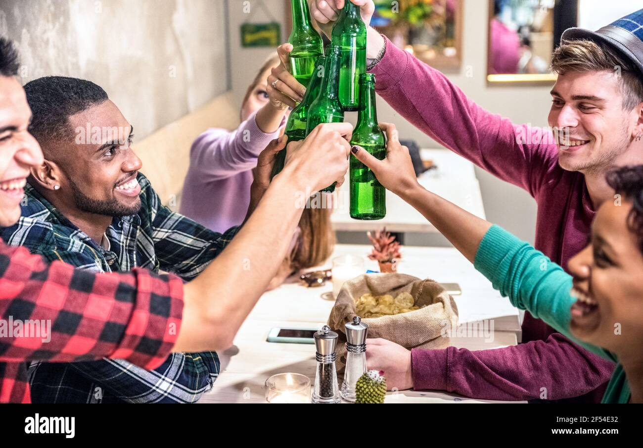 Multiracial friends group drinking and toasting beer at cocktail bar restaurant - Friendship concept with young people enjoying time together Stock Photo