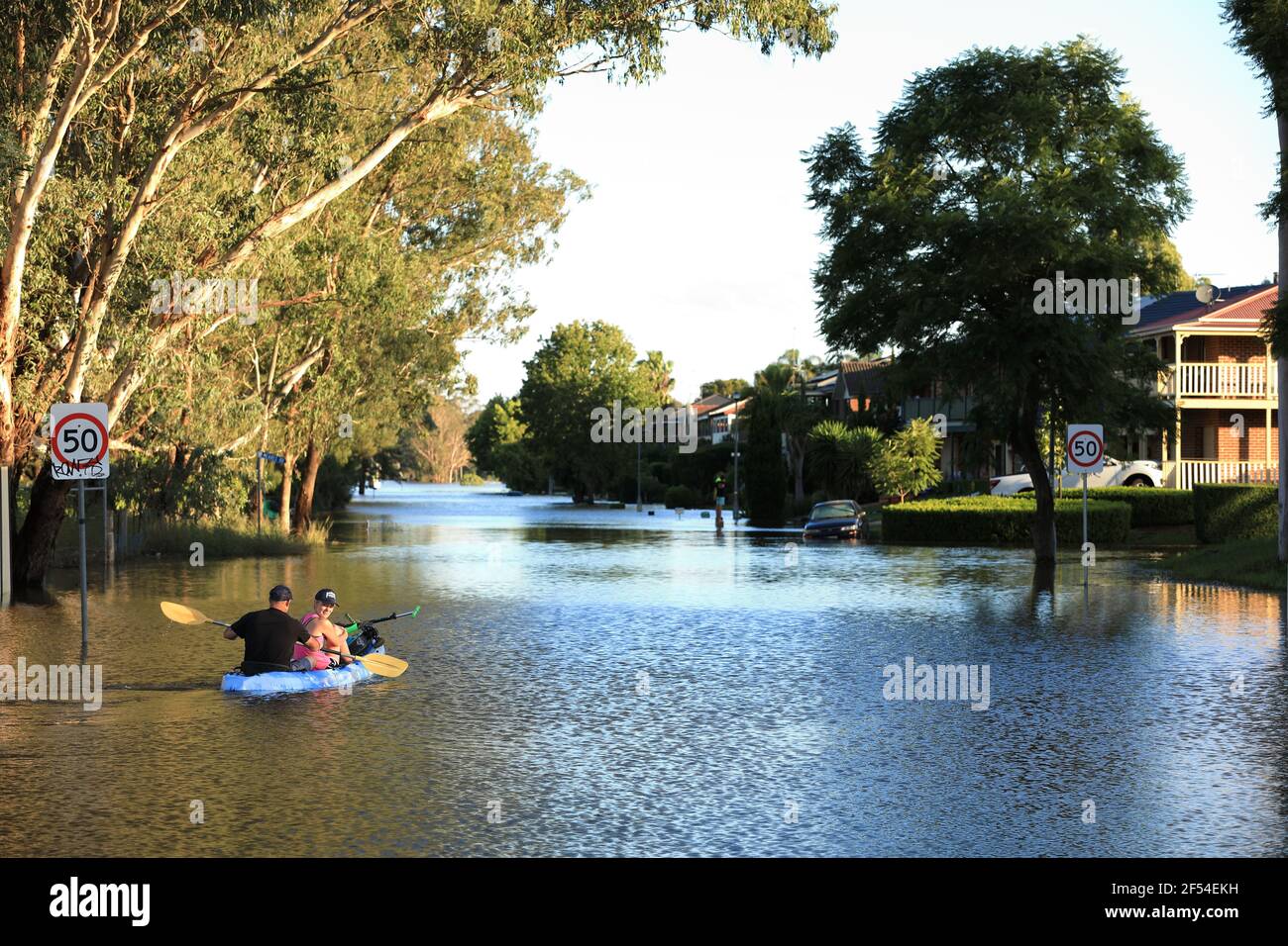 A man and a woman in a kayak paddling up a flooded street at McGraths Hill during the March 2021 Hawkesbury-Nepean River flood, Australia. Stock Photo