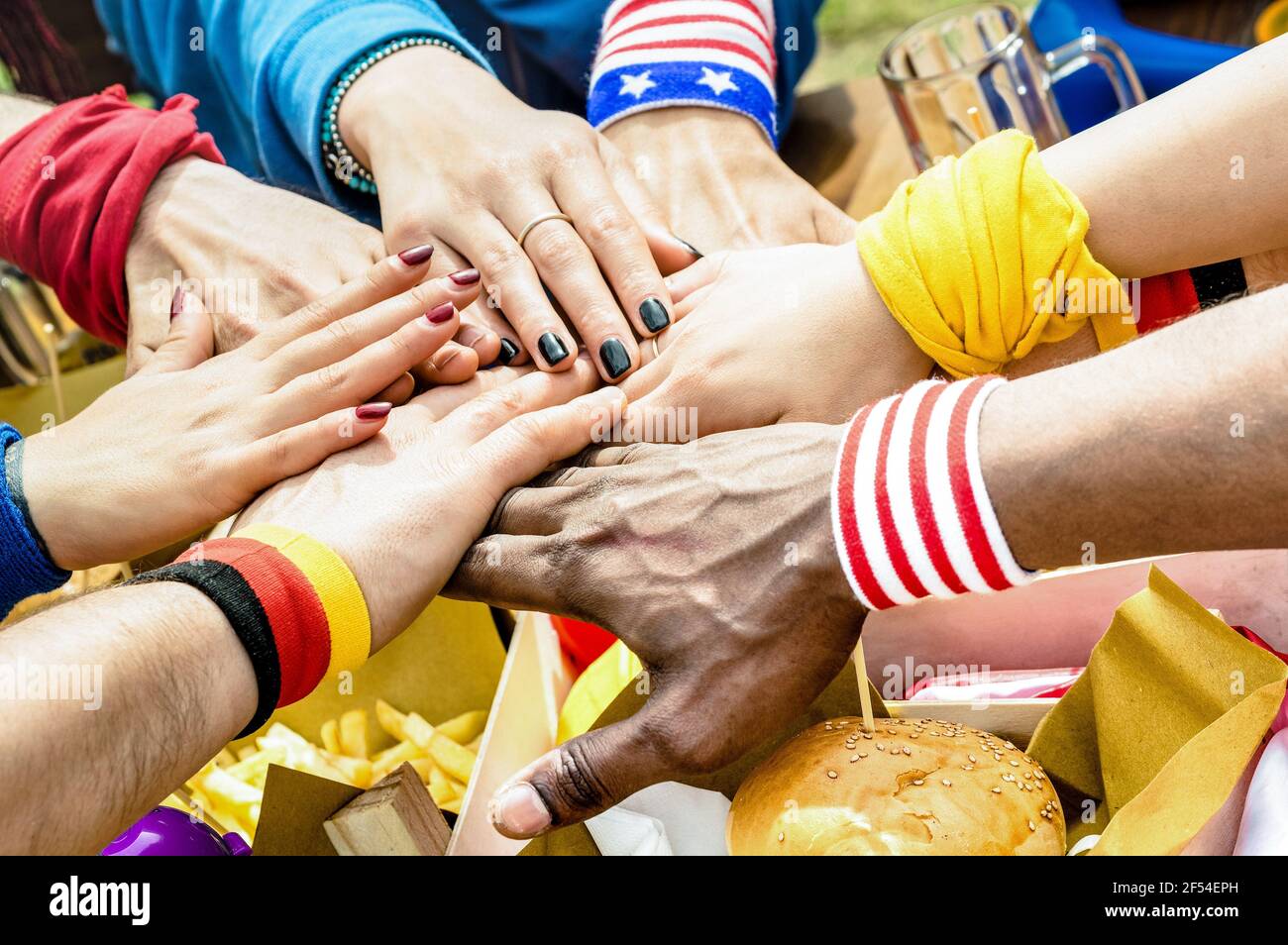 Top side view of multiracial hands of football supporter friend sharing street food - Friendship concept with soccer fan enjoying food together Stock Photo