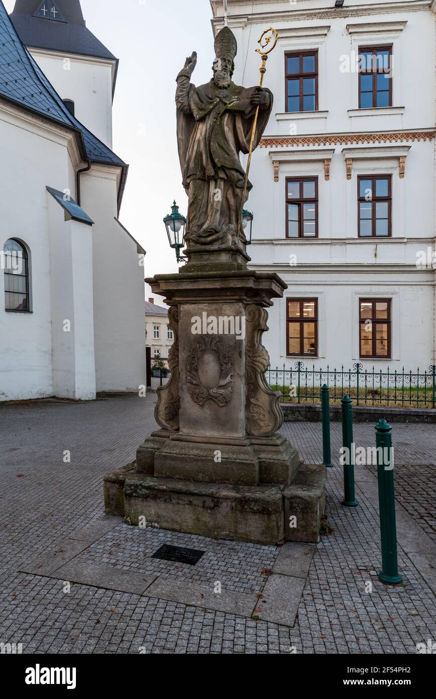 Statue of Saint Patrick on Masarykovo namesti square with Kostel Povyseni sv. Krize churh on the background in Karvina city in Czech republic Stock Photo