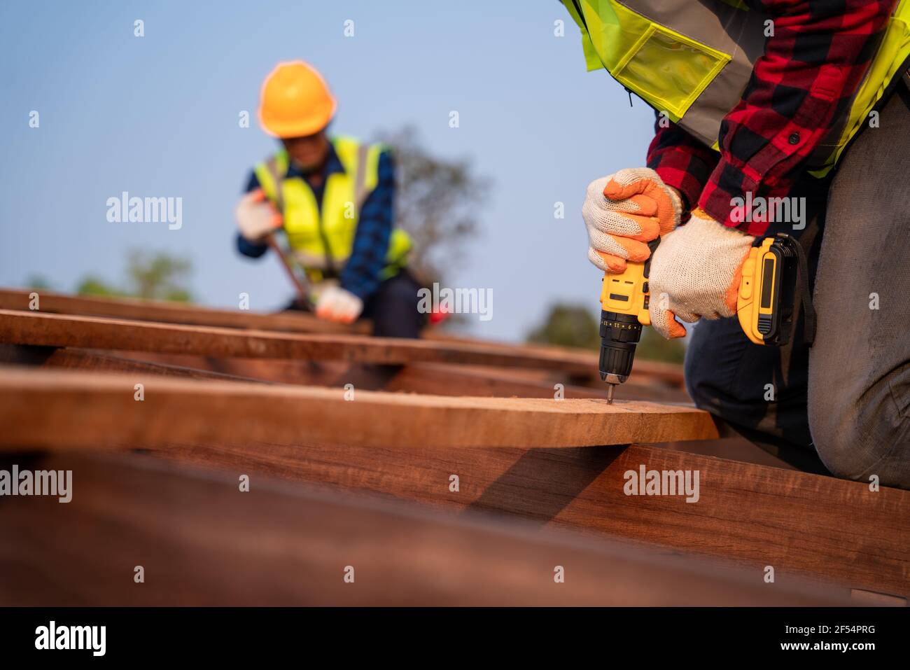 Close up roofer working on roof structure of building on construction site, Roofer using air or pneumatic nail gun and installing on wooden roof struc Stock Photo