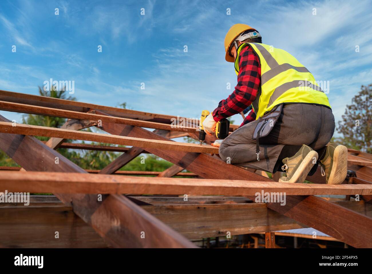 Asian roofer working on roof structure of building on construction site, Roofer using air or pneumatic nail gun and installing on wooden roof structur Stock Photo