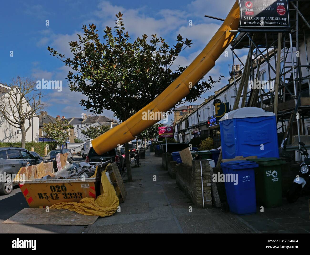 Builders' chute from scaffolding to skip in South London street Stock Photo