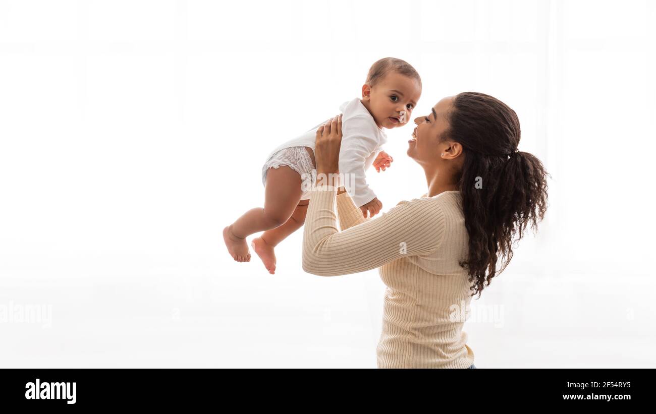 African Mommy Carrying Baby Toddler Playing With Infant, White Background Stock Photo