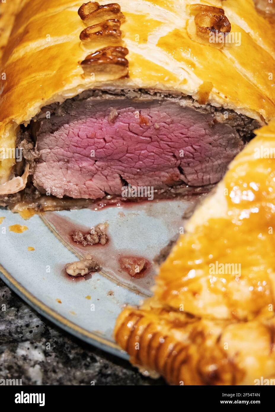 Beef Wellington, cut to show rare cooked fillet beef layered with chestnut mushrooms, parma ham and puff pastry (beef en croute); and oven cooked; UK Stock Photo