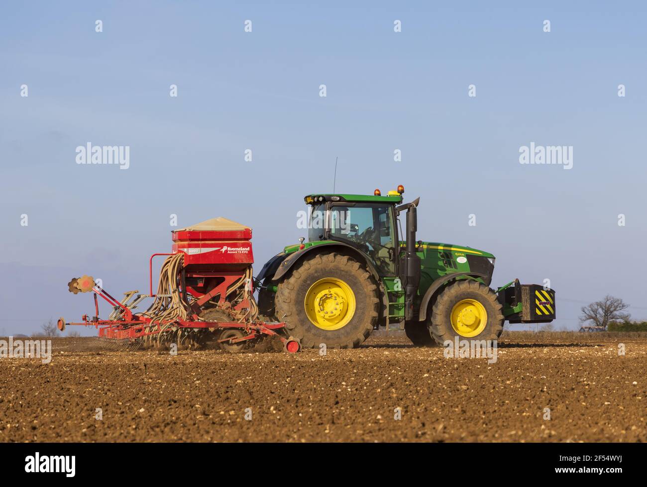 Farmer with a tractor in a field sowing seeds in early spring.  March 2021. Stock Photo