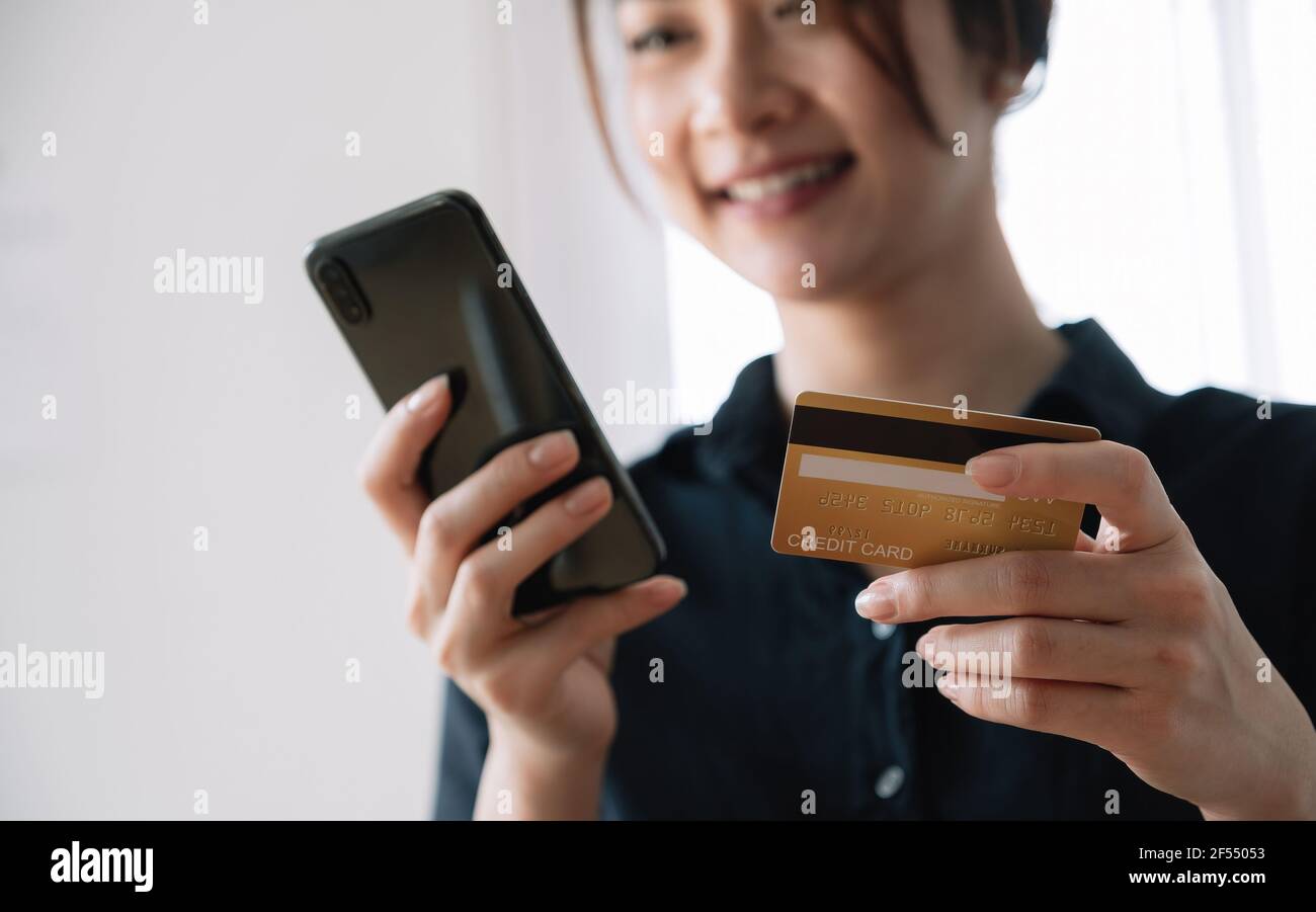 Asian woman making online payment using laptop and credit card for shopping at home. Stock Photo
