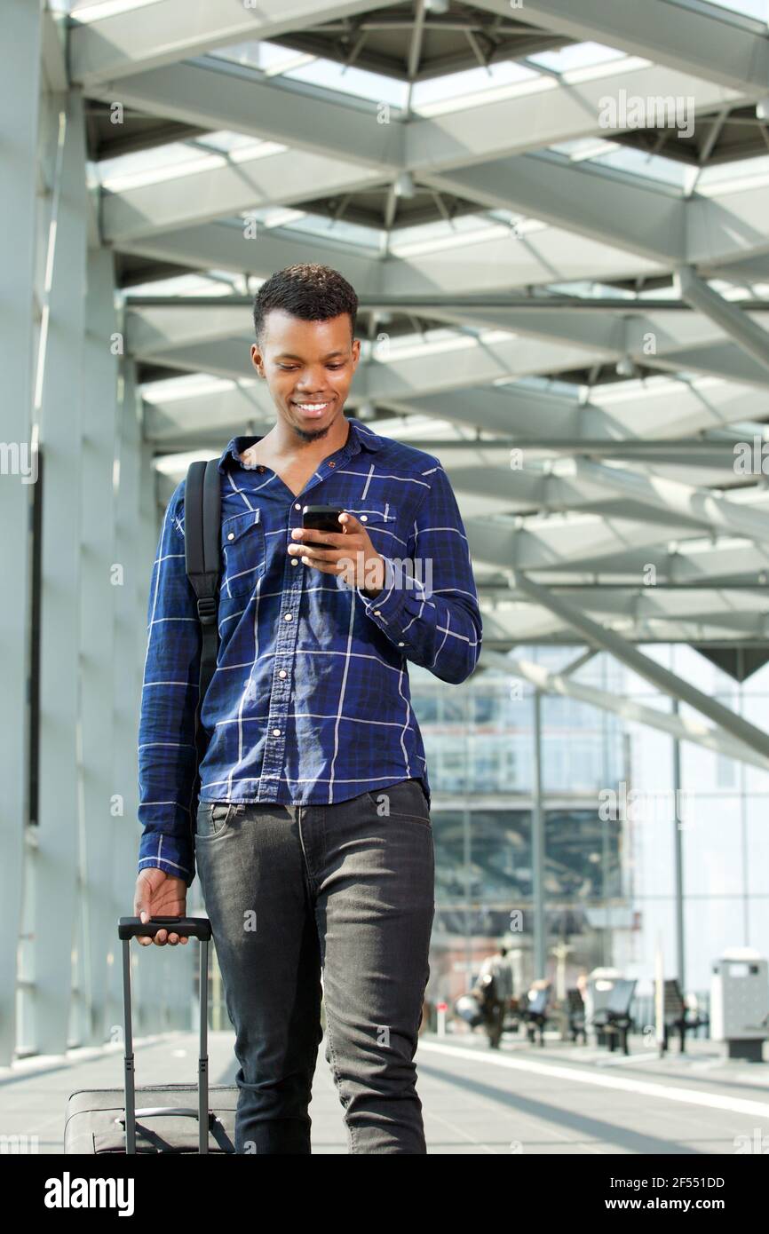 Portrait of man walking in airport with luggage and smart phone Stock ...