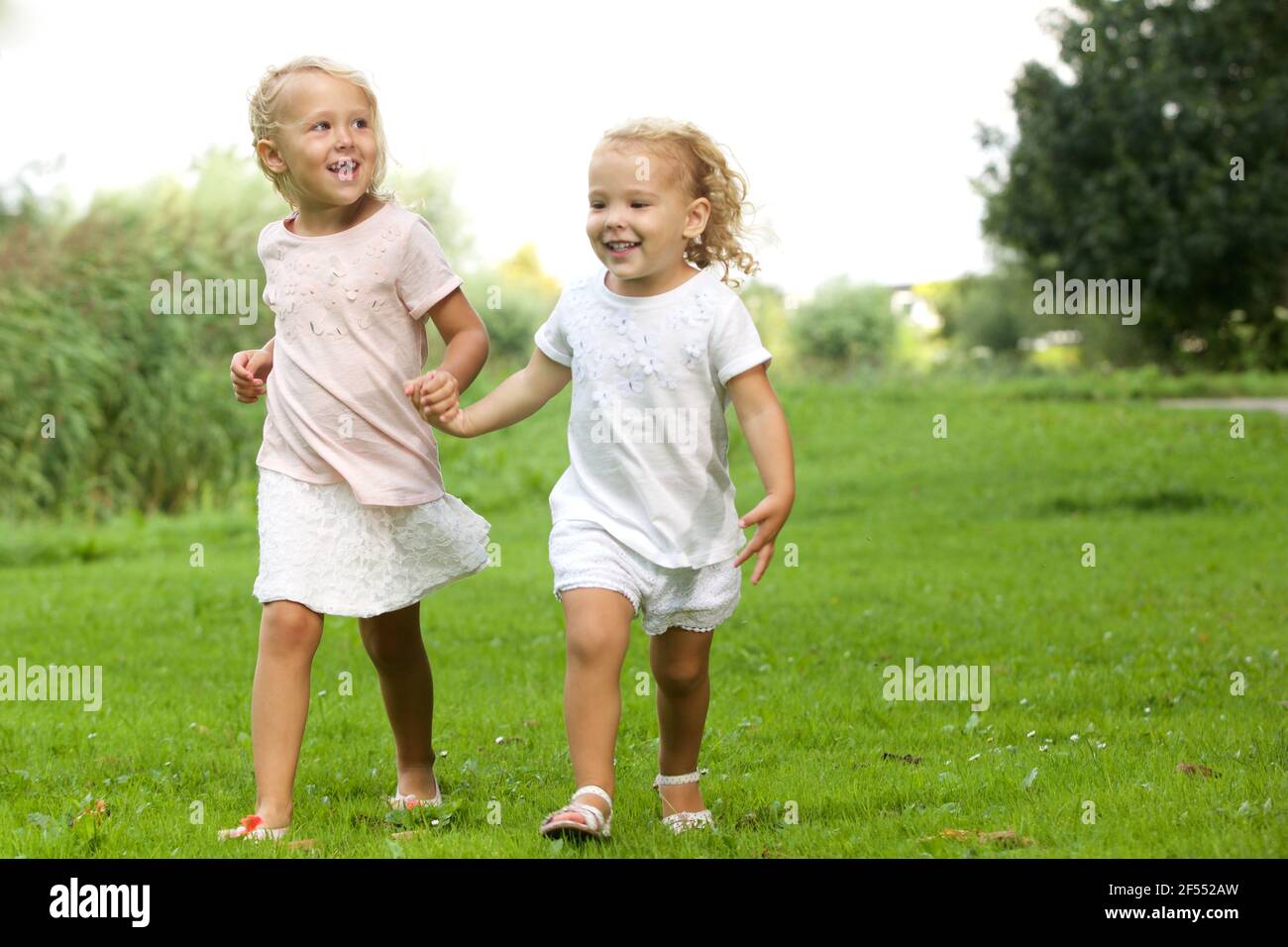 Portrait of two little girls walking in the park holding hands Stock ...
