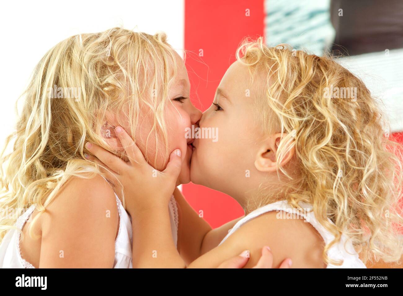 Close up portrait of cute little girls kissing each other at home Stock Photo