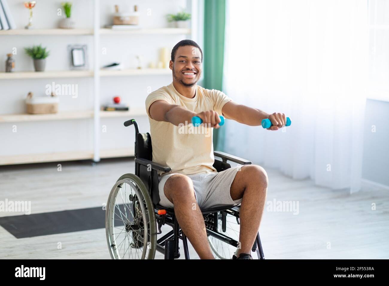 Rehabilitation of disabled people. Young African American man in wheelchair working out at home