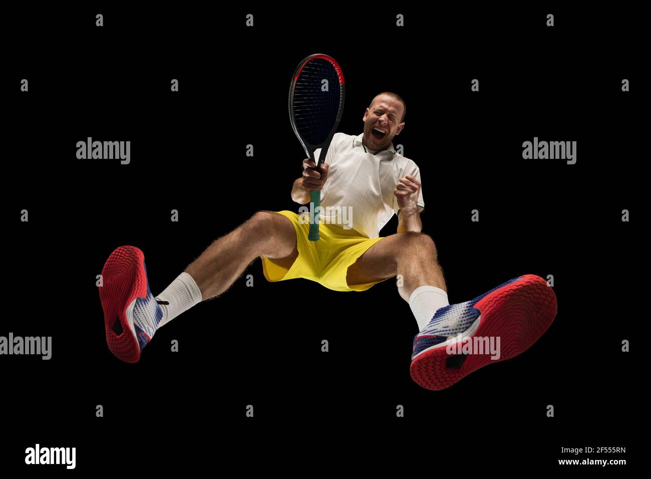 Young caucasian tennis player in action, motion isolated on black background, look from the bottom. Concept of sport, movement, energy and dynamic. Stock Photo