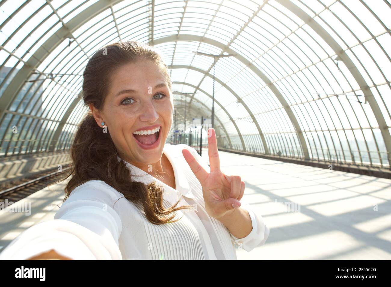 Close up portrait of young laughing woman taking selfie with peace sign ...