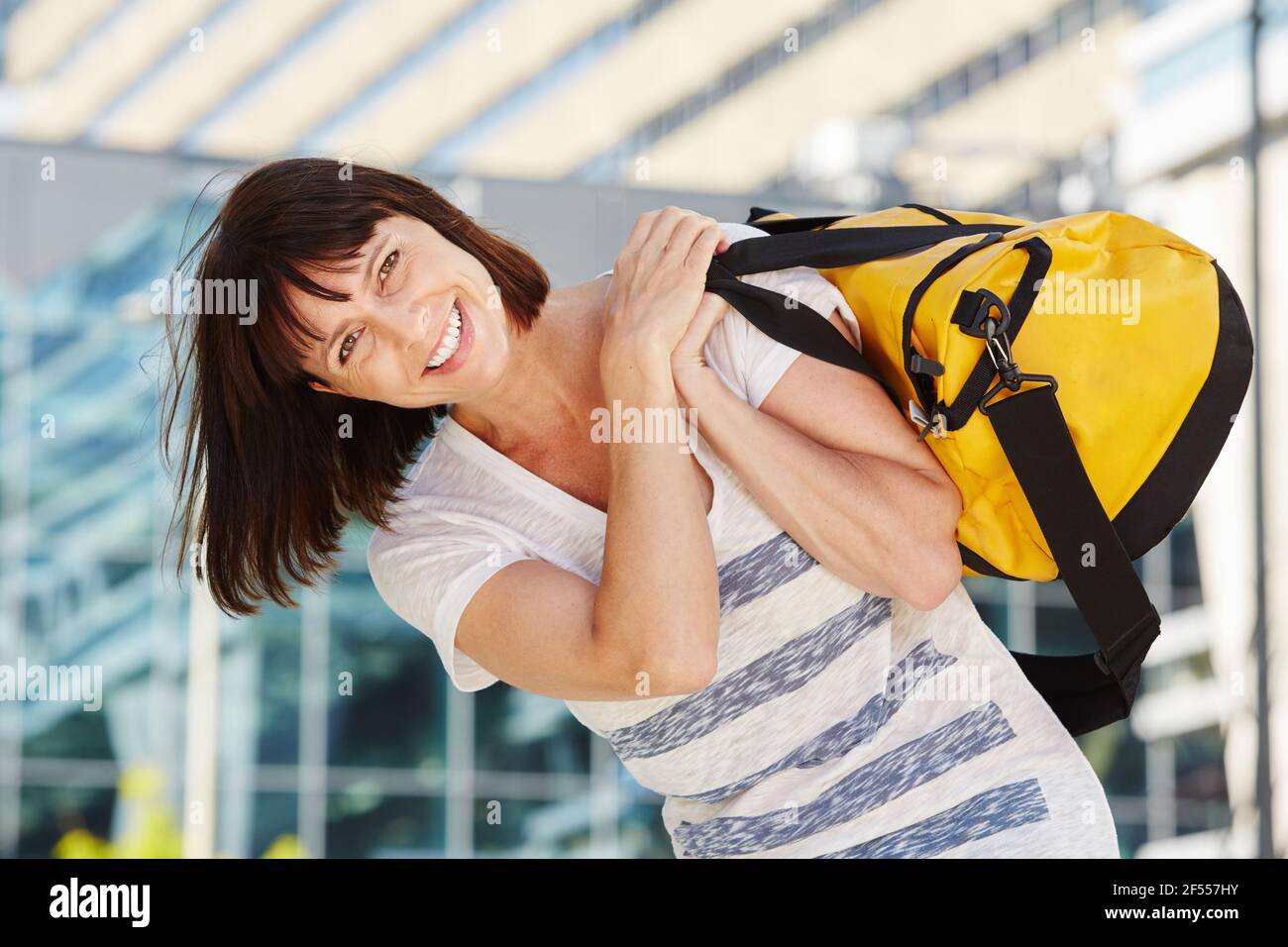 Portrait of happy traveler carrying duffel bag over shoulder Stock