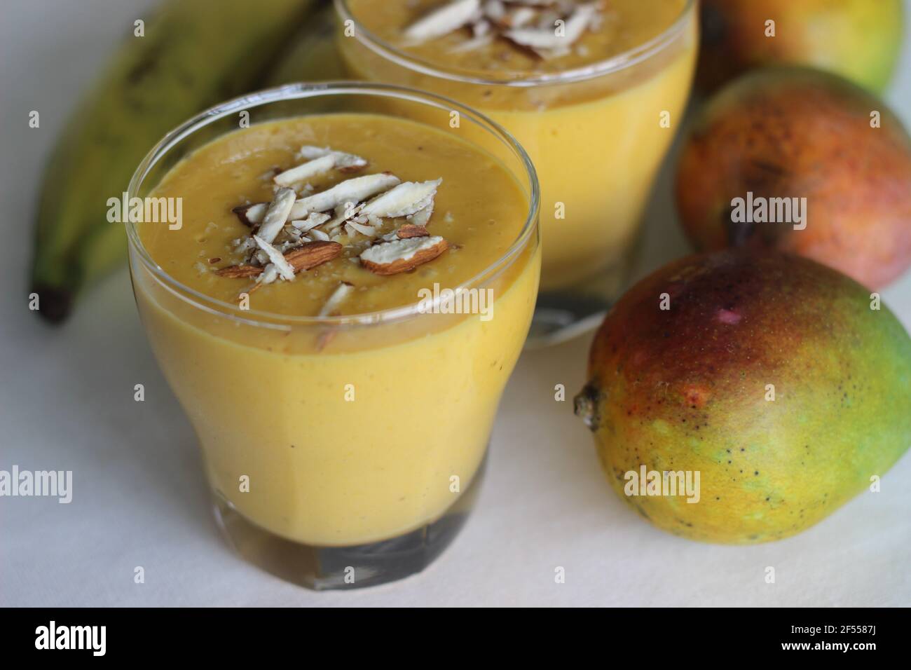 Mango Banana Smoothie, A deliciously thick and creamy banana smoothie bursting with mango flavour. Made with only 5 simple ingredients. Shot on white Stock Photo