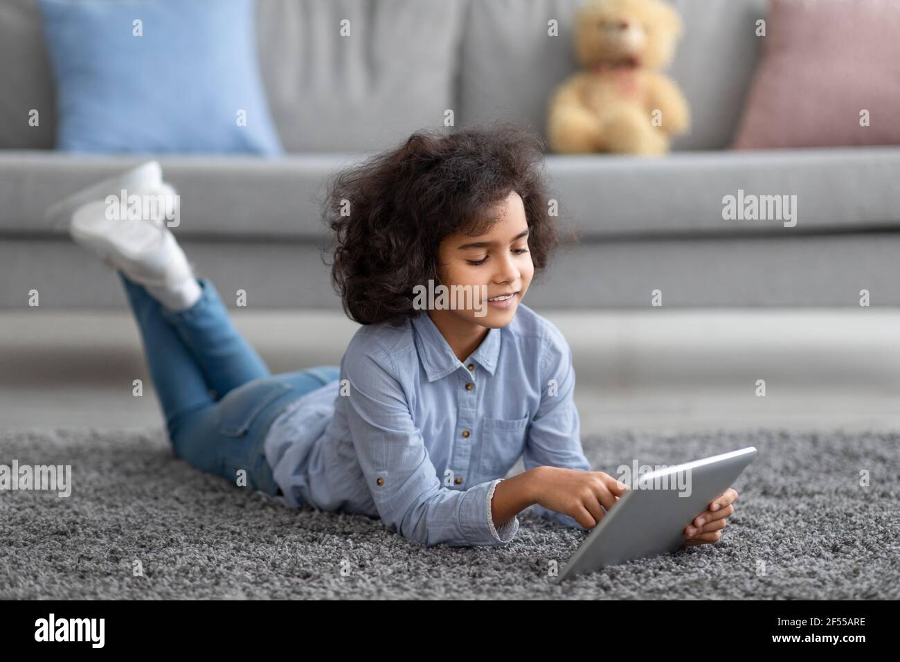 Afro girl using digital tablet,lying on floor carpet Stock Photo - Alamy