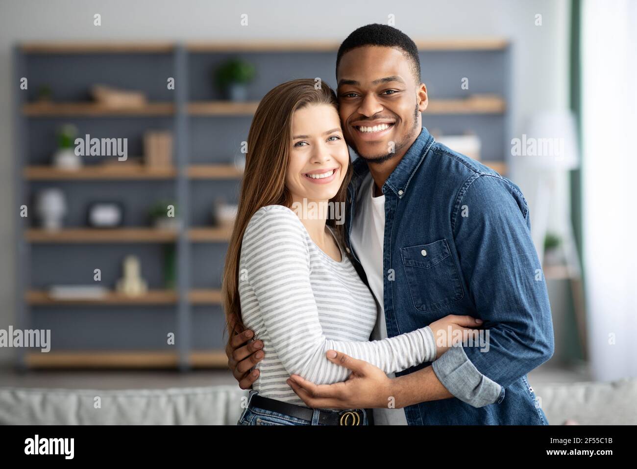 portrait-of-romantic-interracial-couple-embracing-and-smiling-at-camera-2F55C1B.jpg