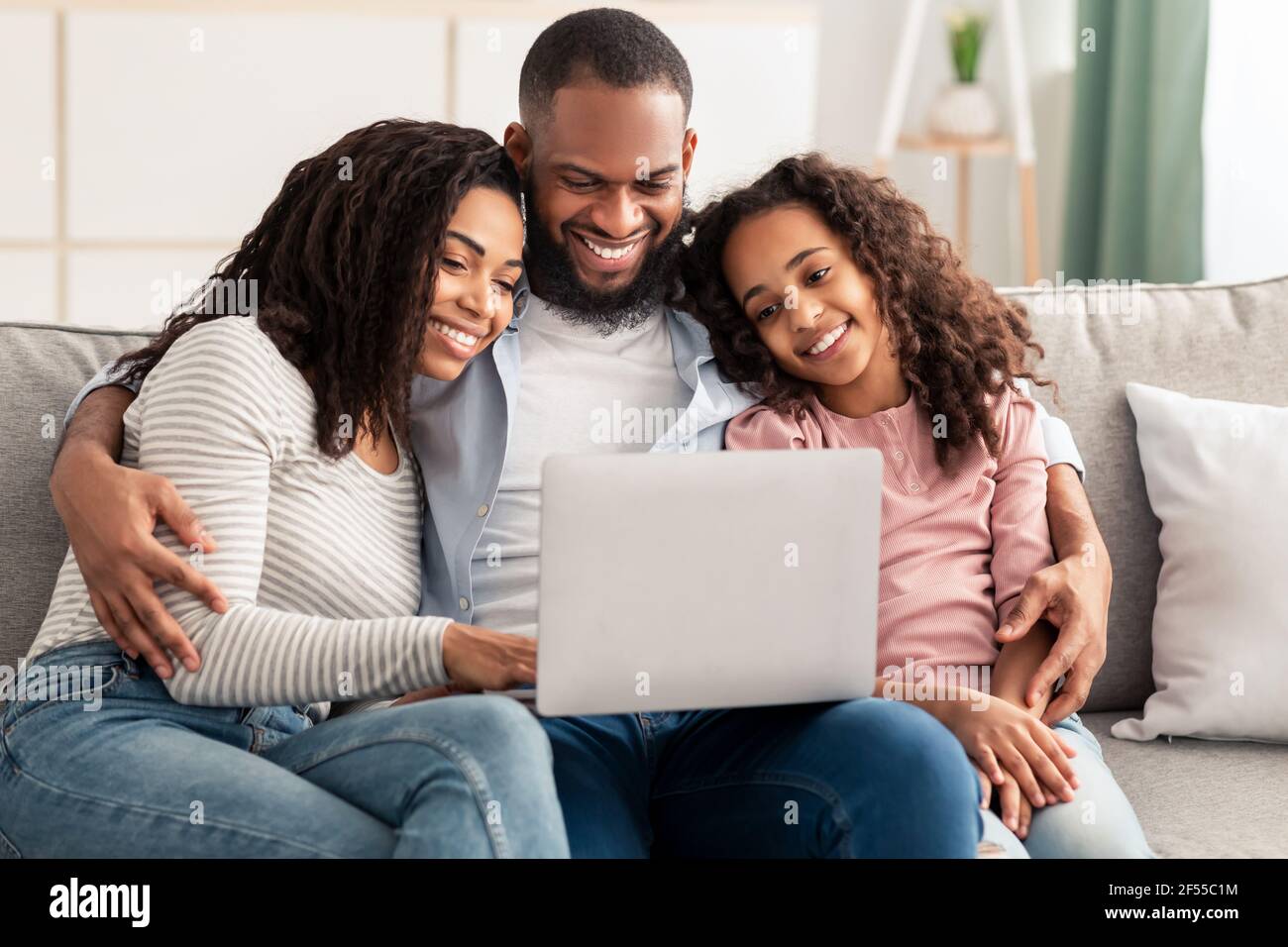 Happy African American family using laptop sitting on the couch Stock ...