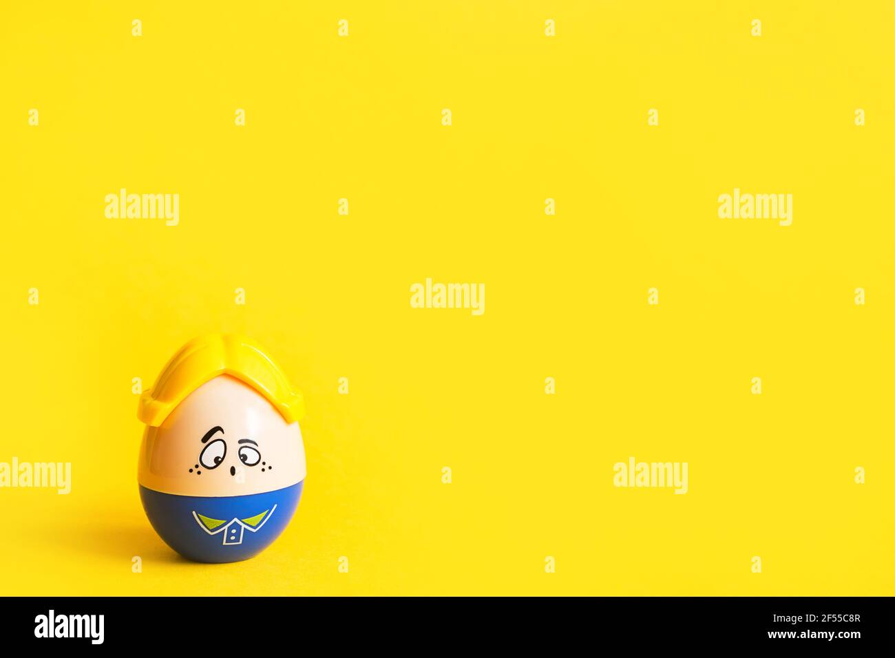 Funny egg toy with a man's sad face on a yellow background. Easter, solitude. Copy space Stock Photo