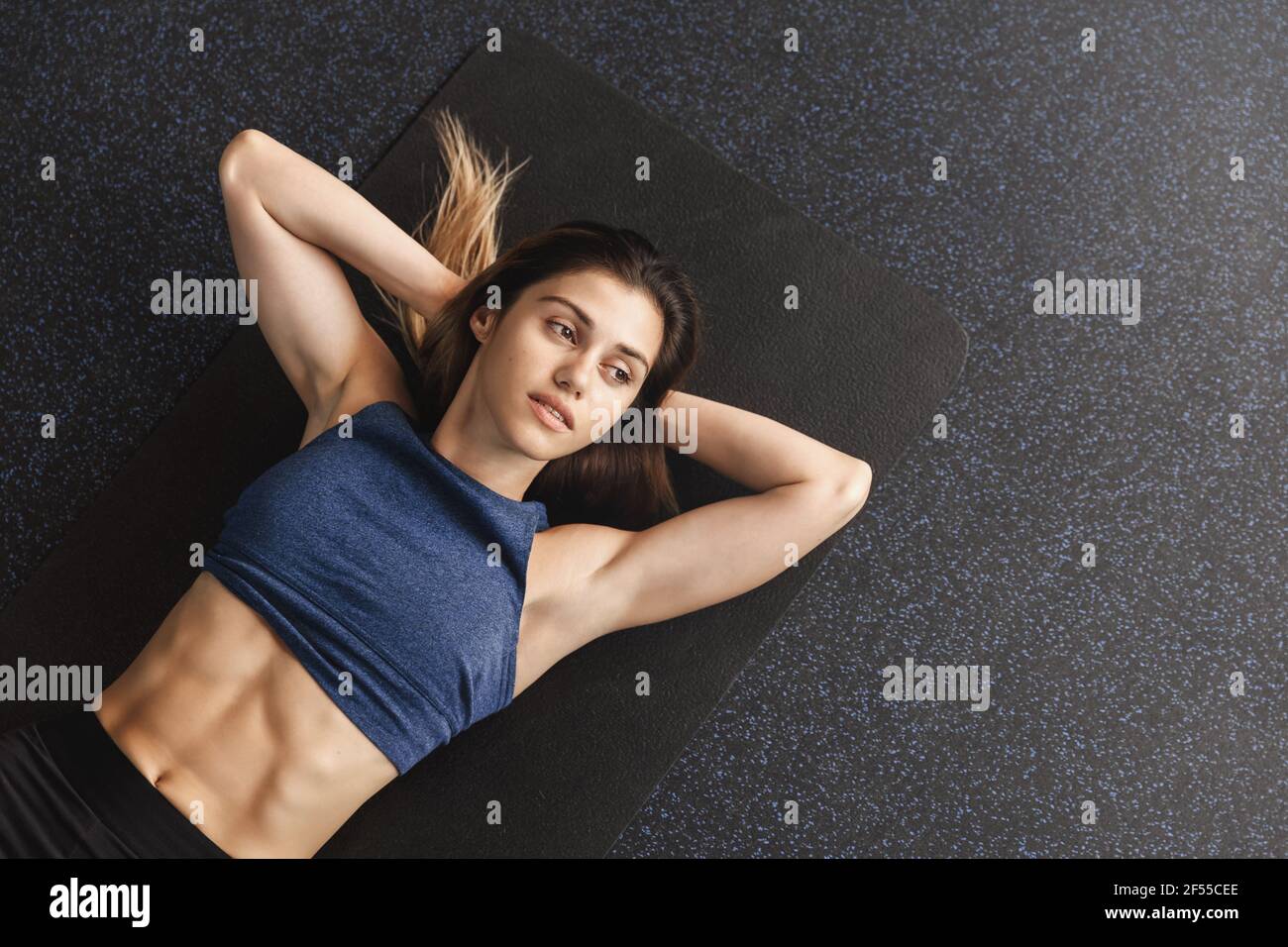 https://c8.alamy.com/comp/2F55CEE/bodycare-sports-and-workout-concept-motivated-sportswoman-working-hard-on-getting-abs-muscles-fit-lying-black-rubber-mat-gym-floor-warm-up-2F55CEE.jpg
