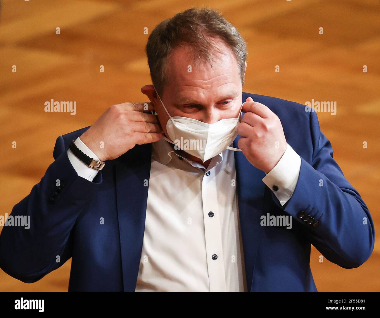 Hamburg, Germany. 24th Mar, 2021. Jens Kerstan (Bündnis90/Die Grünen), Senator for Environment and Energy in Hamburg, puts on his mouth-nose protection after his speech in the current affairs hour during a session of the Hamburg Parliament in the Great Festival Hall in the City Hall. Credit: Christian Charisius/dpa/Alamy Live News Stock Photo