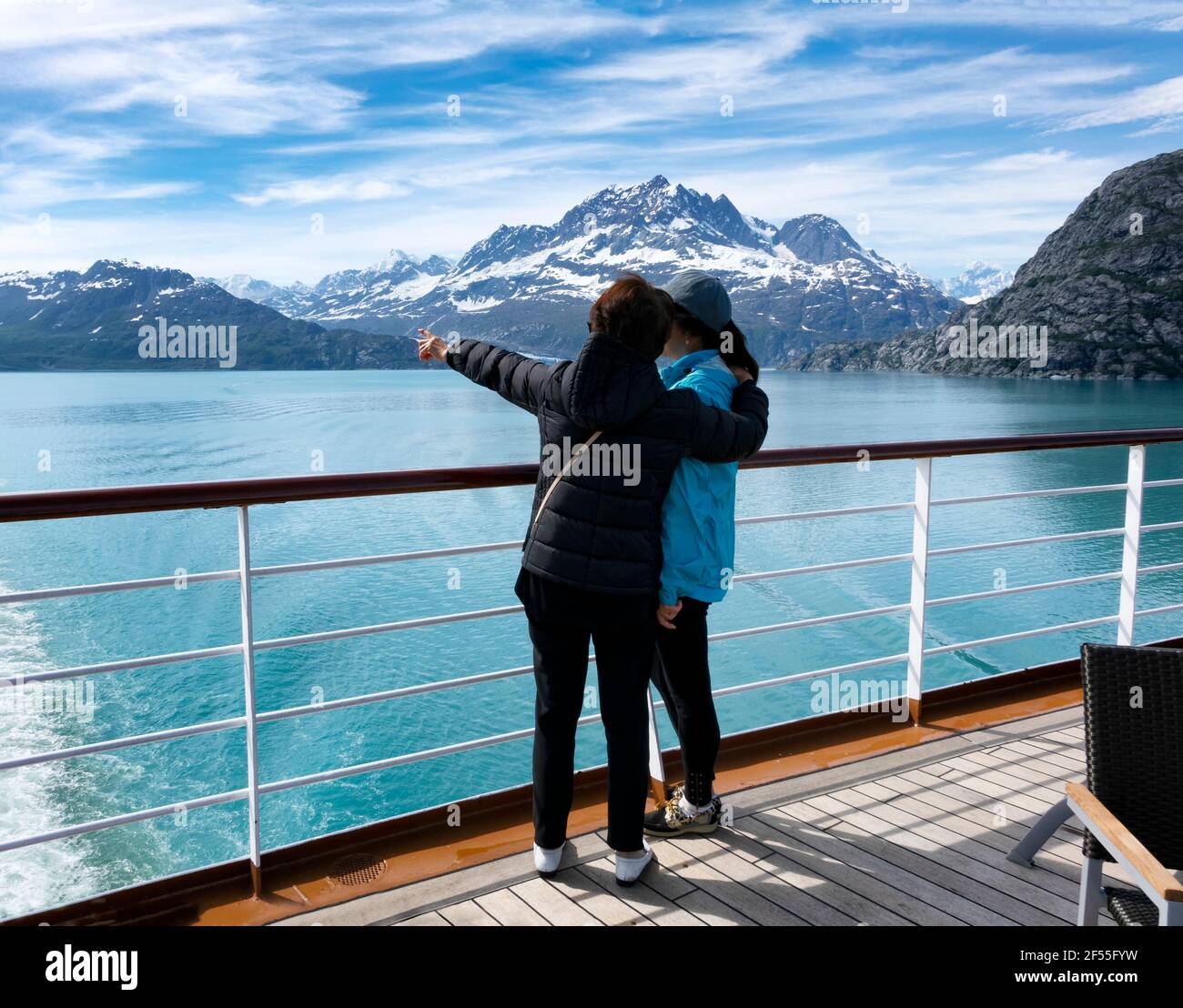 Mother holding her daughter while pointing out mountains and glaciers on Alaska tour via ship Stock Photo