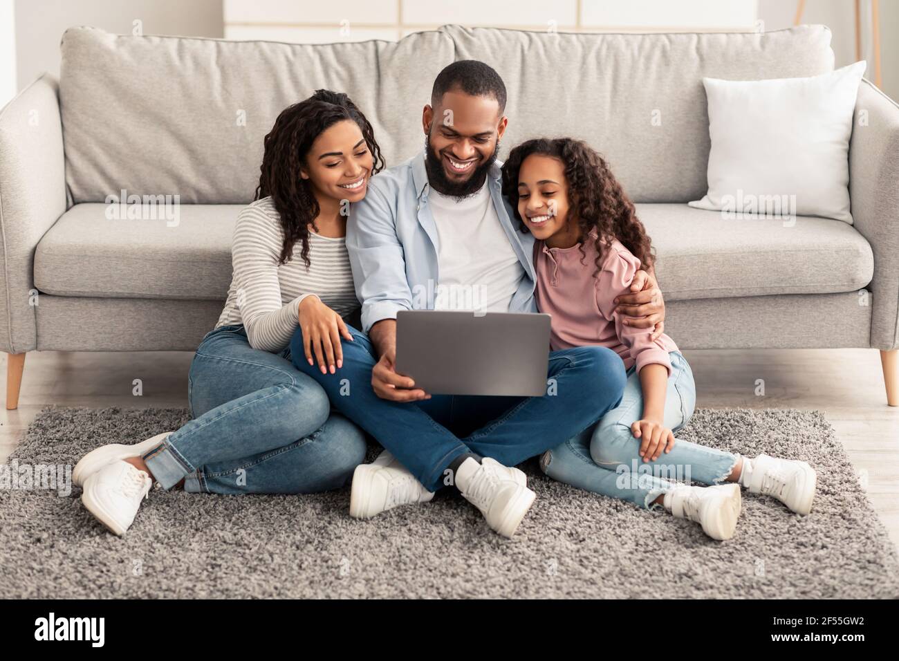 Happy African American family using laptop sitting on the floor Stock ...