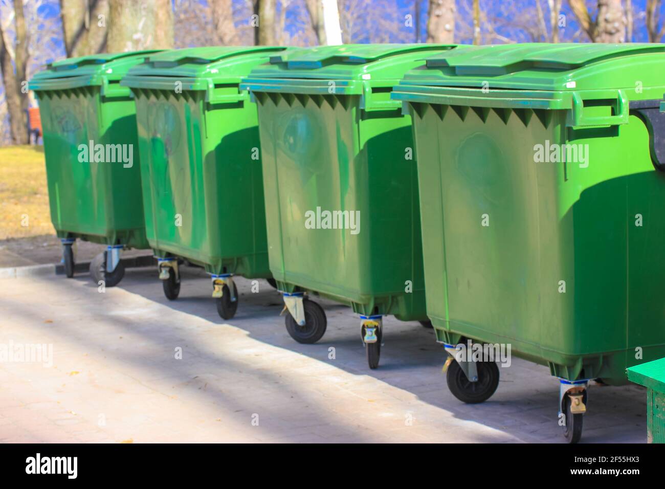 Large green plastic trash cans on city street. Containers on wheels