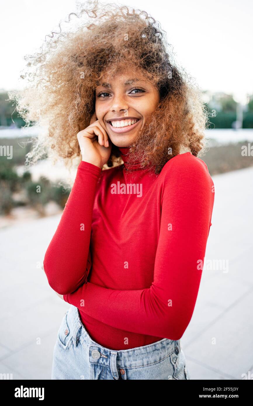 Smiling Afro woman standing with tousled hair Stock Photo
