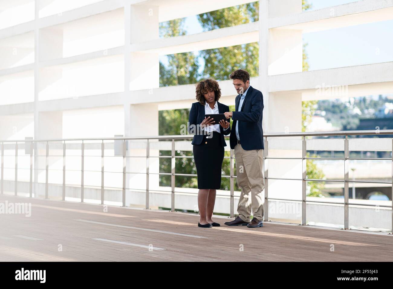 Business team working on digital tablet while standing by railing Stock Photo