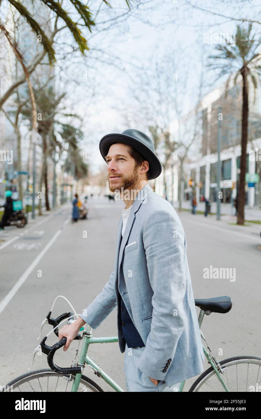 Businessman with bicycle walking in city while looking away Stock Photo
