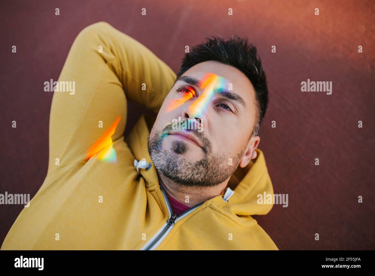 Bearded man with spectrum on face while lying down ground Stock Photo