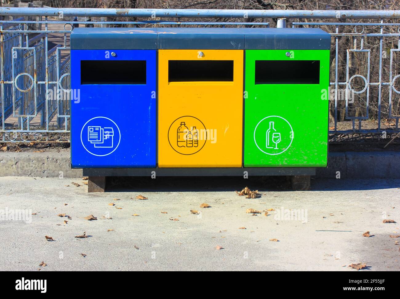 Three metal blue, green, yellow recycle bins at urban environment