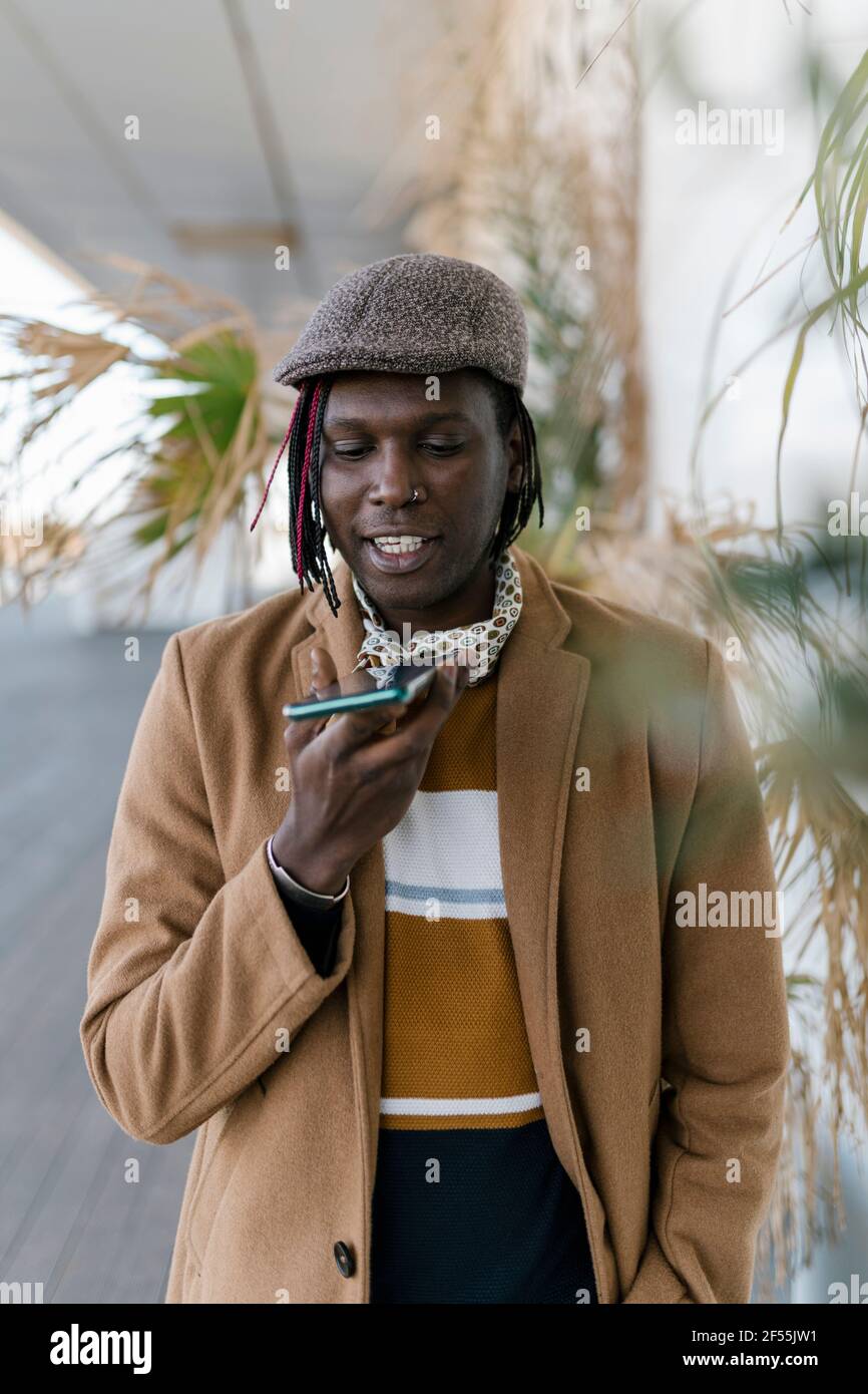 African man talking on smart phone through speaker Stock Photo