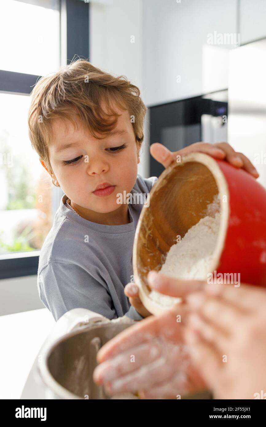 Brother and sister looking into dough mixer on kitchen counter Stock Photo