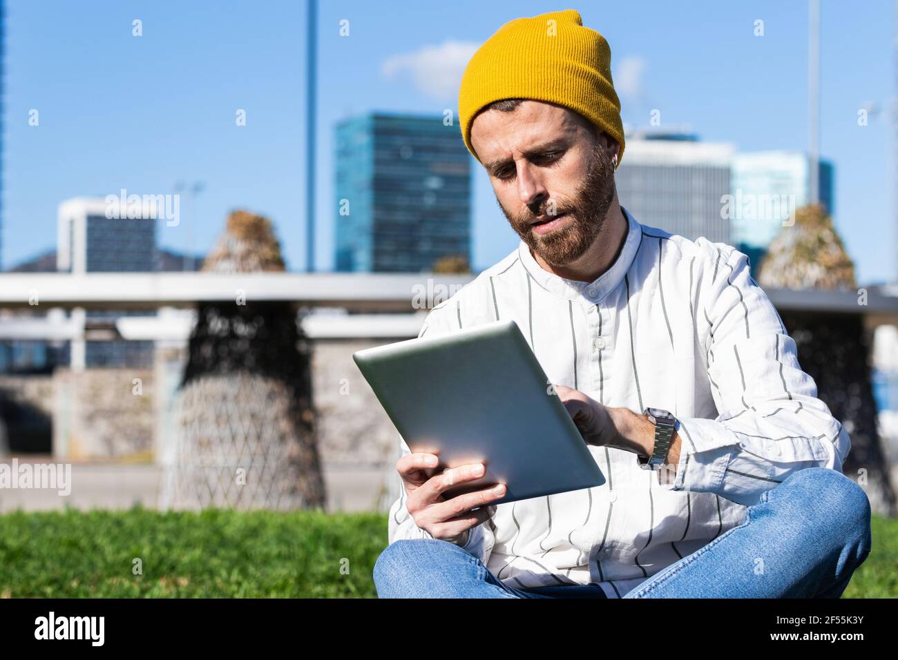 Handsome man using digital tablet while sitting at park during sunny day Stock Photo